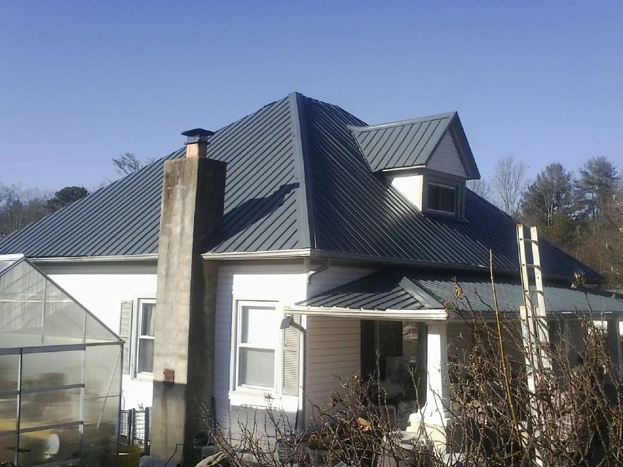 Dark blue standing seam metal roof on a white farmhouse with dormer — Slate & Tile Roof Repair by Roofing Brothers in Tippecanoe
