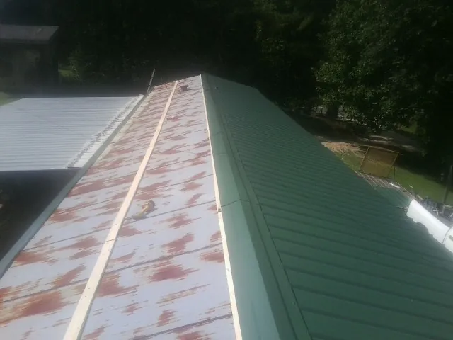 Old rusted panels beside newly installed green metal roofing — Wind Damage Roof Repair by Roofing Brothers in Tippecanoe
