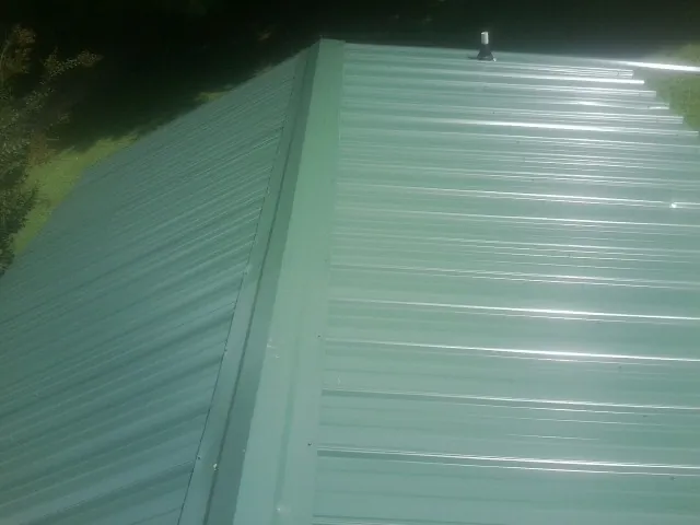 New green metal panels meeting at the ridge of a roof — Flat Roof Repair work by our crew in Tippecanoe