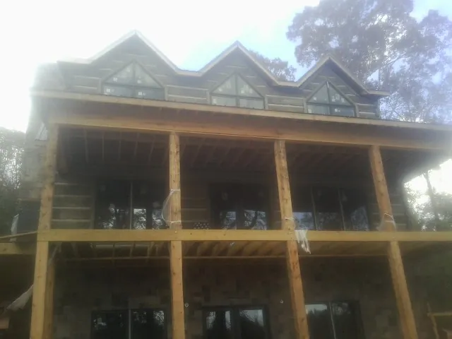 Dormers and porch framing on a large log home under construction — Roof Coating work by our crew in Tippecanoe
