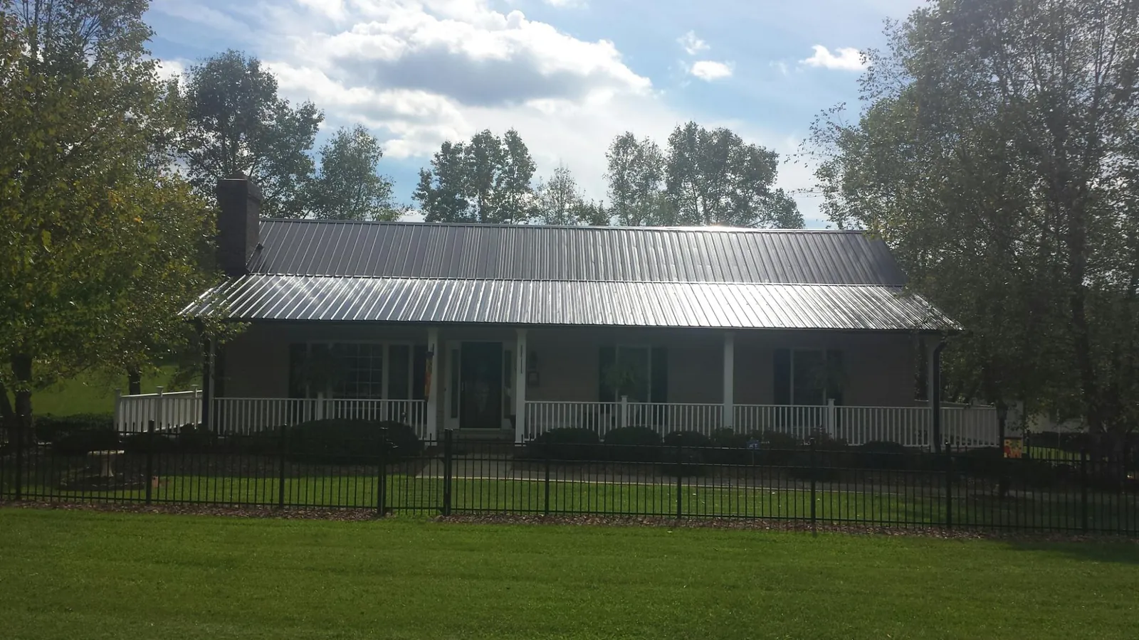Gray metal roof on a brick ranch with a full width front porch — Gutter Guard Installation work by our crew in Tippecanoe