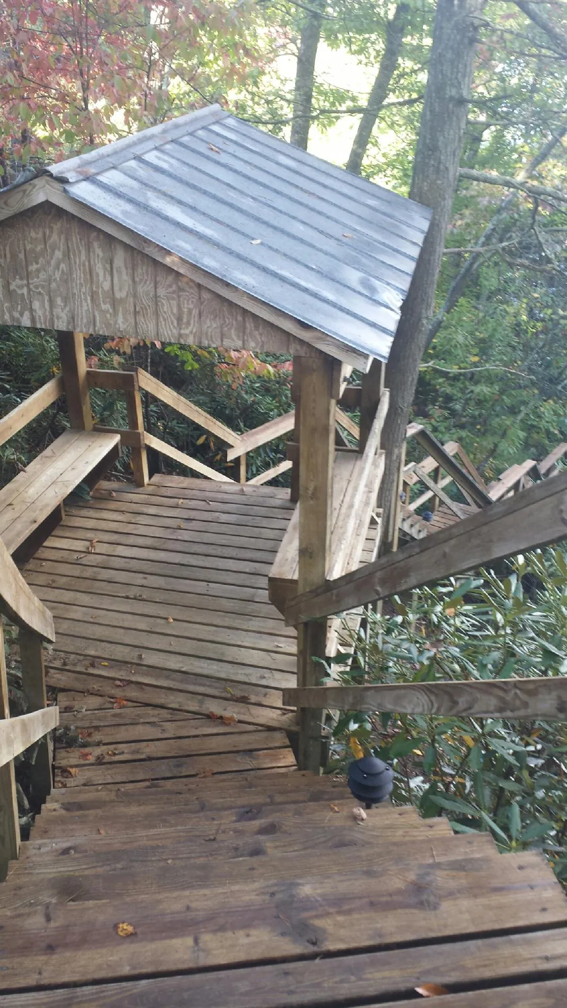 Metal roofed shelter over wooden steps on a wooded walkway — Skylight Repair & Installation work by our crew in Tippecanoe