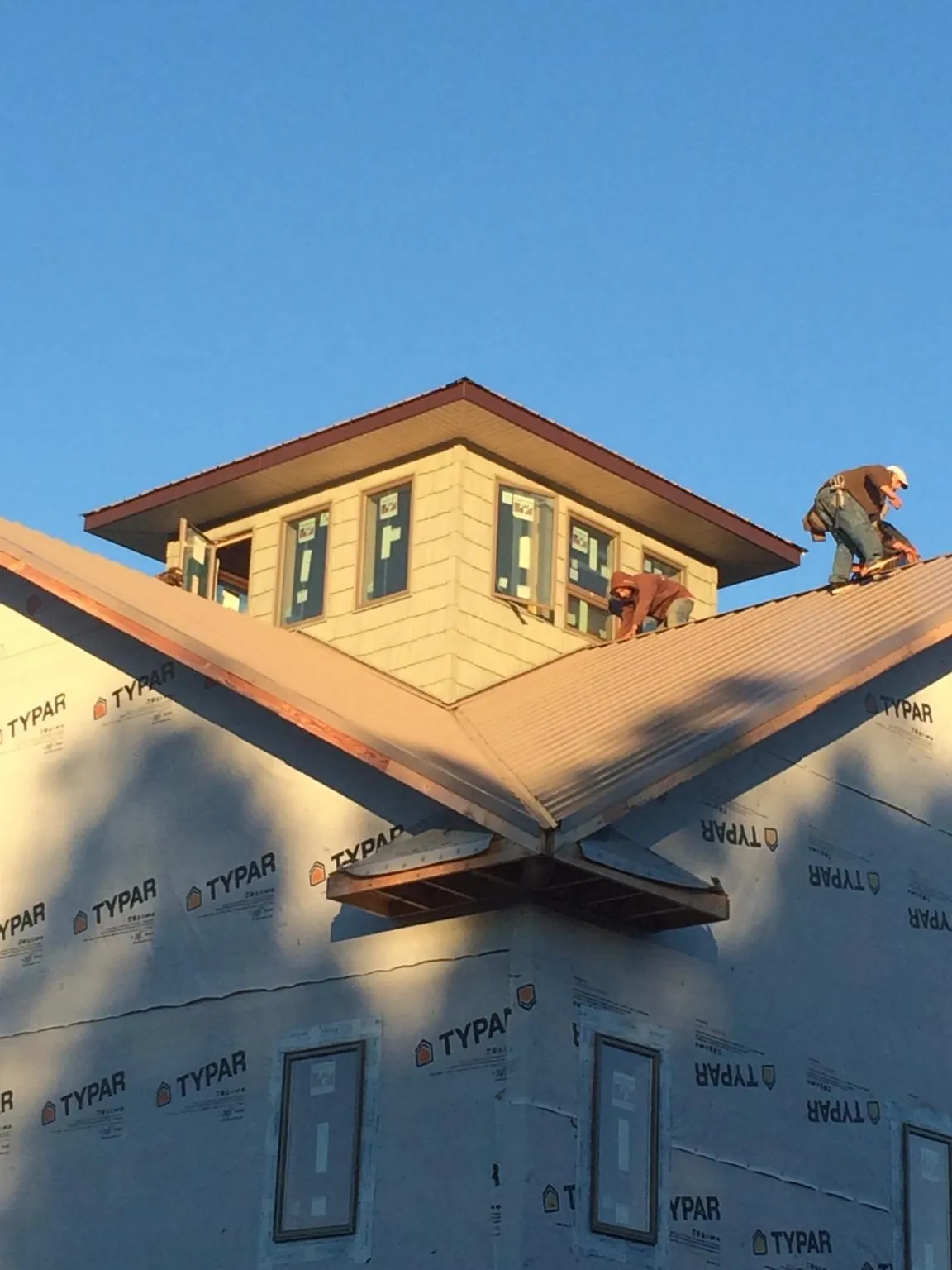 Roofers working around a rooftop cupola on a new metal roof at sunset — Roof Waterproofing in Tippecanoe by Roofing Brothers